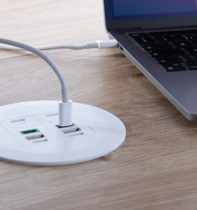 A close-up image of a tabletop with built-in cable outlets