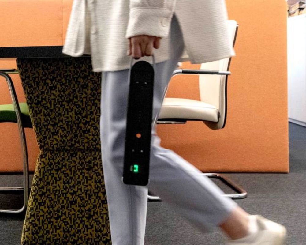 A close-up image of a person walking and holding a portable black battery