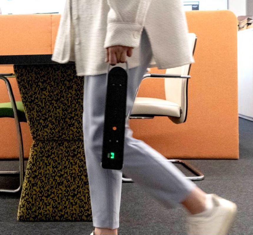 A close-up image of a person walking and holding a portable black battery