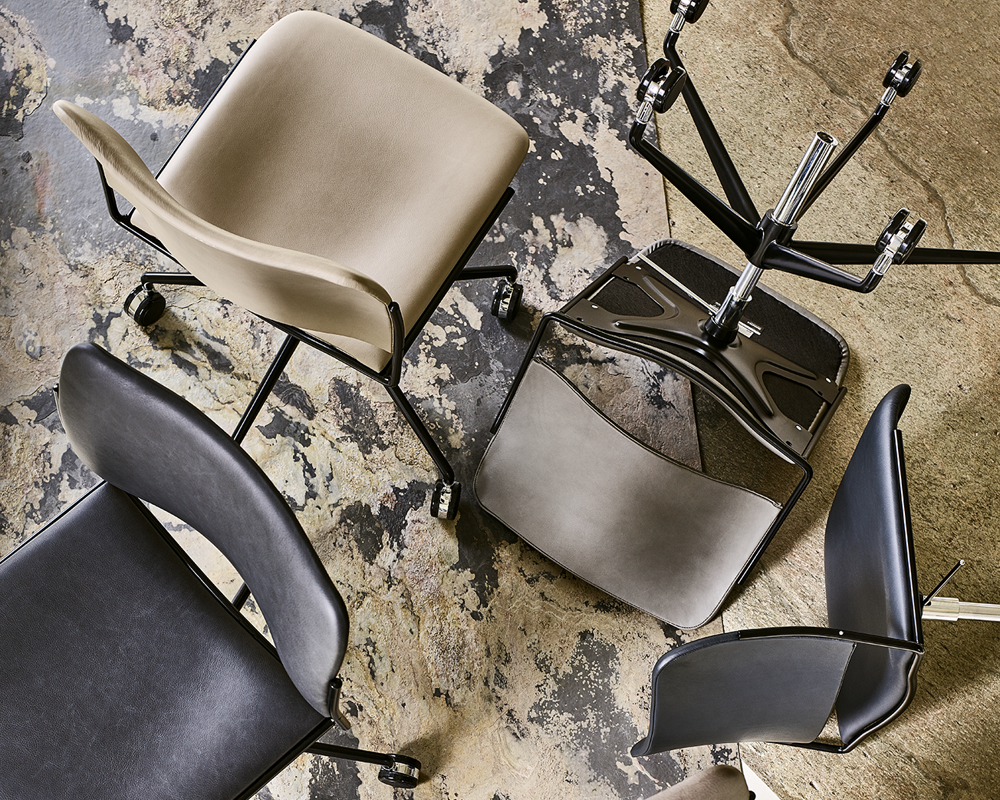 An artistic installation of a group of four leather-upholster 40/4 swivel chairs on a patterned floor